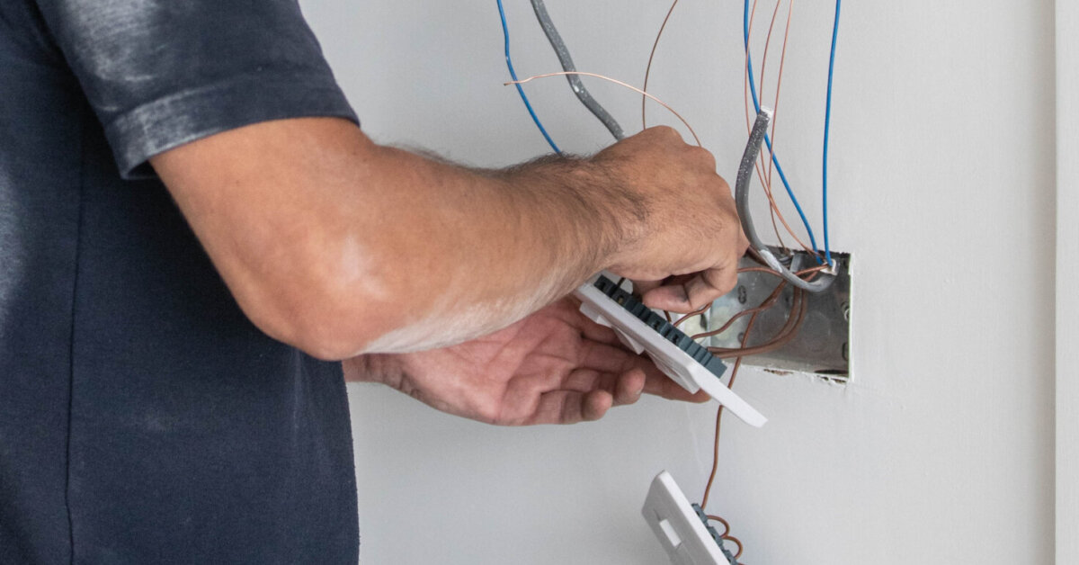 Electrician Tradesman Carrying Out The Final Wiring Of A Residential Property Connecting Light Switches