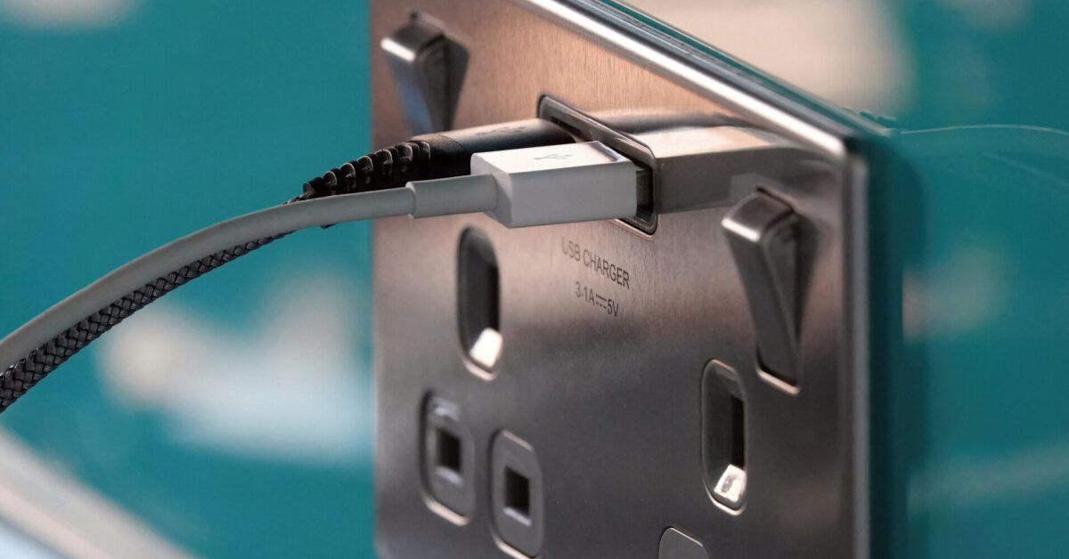 Two Usb Charging Cables Plugged In To A Stainless Steel Electric Socket In A Kitchen